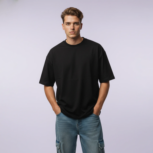 Man wearing a black t-shirt and blue jeans against a plain background