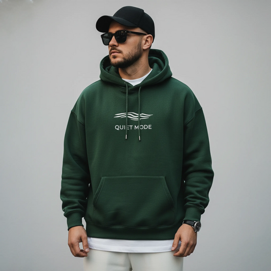 Man wearing a green hoodie with 'Quiet Mode' logo on a gray background